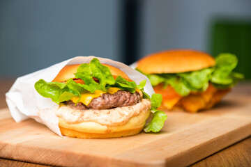 Cheese burger - American cheese burger with fresh salad on wooden board