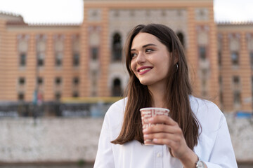 The smiling young woman drinks coffee to Go