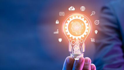 Businessman showing AI artificial intelligence icon in glowing light bulb. Machine learning...