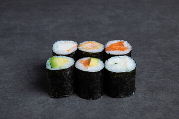 Sushi roll with salmon, avocado and cucumber on black background