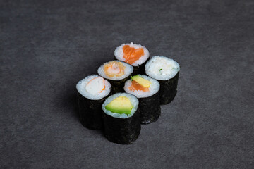 Sushi roll with salmon, avocado and cucumber on black background
