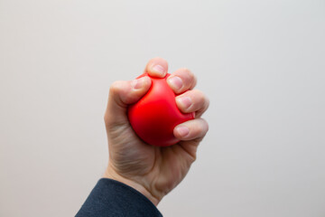 Man squeezing red rubber stress ball on white background