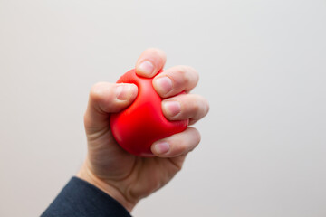 Man`s hand squeezing stress ball in fury during work