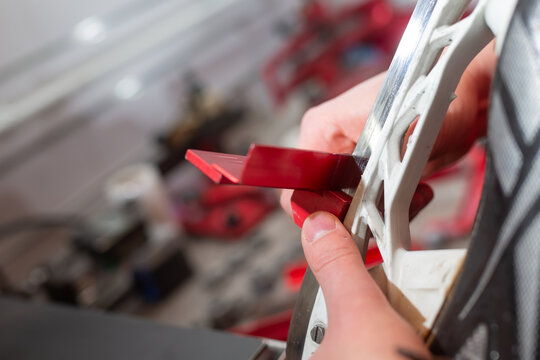 Checking ice hockey skates sharpened edge levels with red precision tool