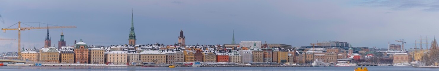 Naklejka na ściany i meble Panorama, the old town Gamla Stan with churches, commuting and tourist boats, a snowy day in Stockholm