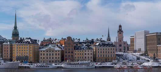 Panorama, the old town Gamla Stan with churches, commuting and tourist boats, a snowy day in Stockholm