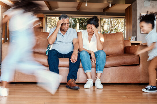 Kids running, stress and grandparents on sofa tired and chaos in living room with frustrated grandpa and grandma. Parenting burnout, hyperactive children playing in home with old woman and man