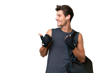 Young sport caucasian man with sport bag over over isolated background pointing to the side to present a product