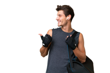 Young sport caucasian man with sport bag over over isolated background pointing to the side to present a product