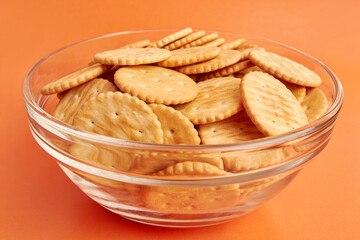 A bowl of round crackers on a yellow background. A tasty and sweet snack.