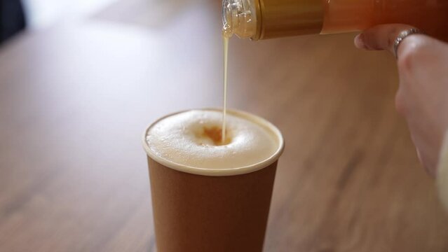 Sweet syrup is poured into a latte glass