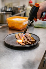 professional chef's hands cooking sliced meat beef brisket in restaurant kitchen