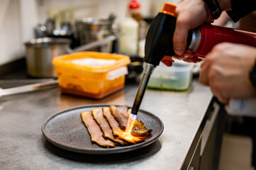 professional chef's hands cooking sliced meat beef brisket in restaurant kitchen