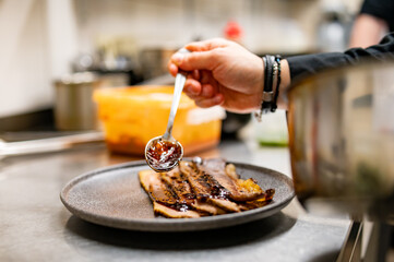 professional chef's hands cooking sliced meat beef brisket in restaurant kitchen