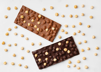Black and milk chocolate with hazelnuts on a white background top view