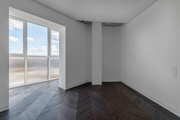 Empty apartment with large floor-to-floor window overlooking nature and blue sky with clouds