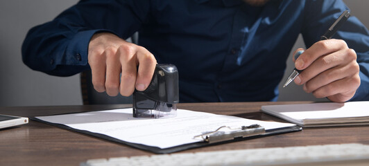 Businessman puts a stamp on the documents in the office.
