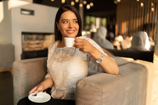 The smiling young woman drinks coffee 