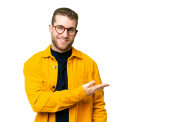 Young handsome blonde man over isolated chroma key background presenting an idea while looking smiling towards