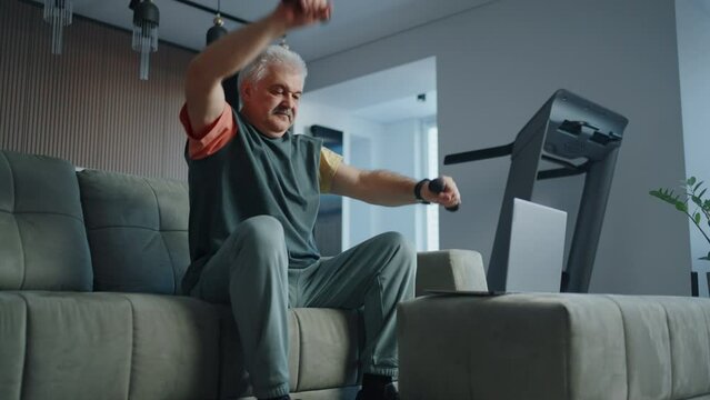 Retired Man Training At Home For Saving Health And Keeping Fit, Watching Online Workout By Laptop