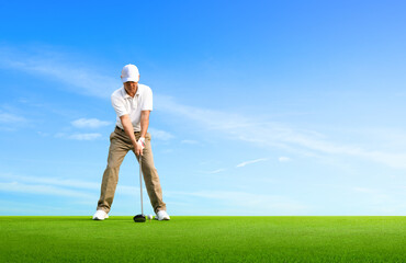 Golf approach shot with driver on golfing ground with blue sky background.