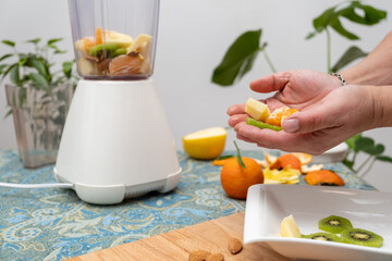 Fruits in hands for a smoothie and a blender in the background
