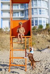a handsome boy of seven years old is playing on the beach with his dog, the guys are playing, having fun, the child is raising a pet, great time together on the beach