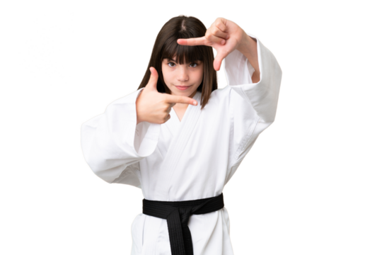 Little Caucasian girl doing karate over isolated background focusing face. Framing symbol