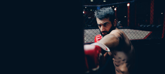 MMA fighter trains with punching bag in gym, dark background banner