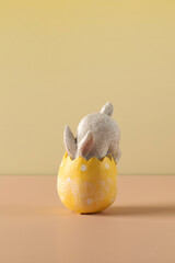 A white rabbit hid in an Easter egg on a yellow background. Festive Easter card.