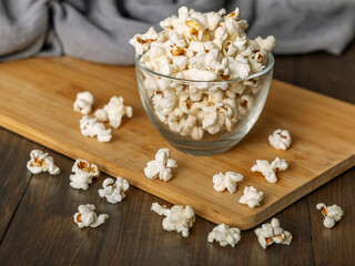 Popcorn in glass bowl on wooden background
