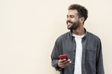 Young handsome man using smartphone in a city. Smiling student men texting on his mobile phone isolated portrait. Modern lifestyle, connection, business concept