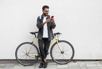 Young handsome man with bicycle over white wall background in a city, cheerful student men with...