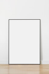 Empty vertical frame mockup standing on floor in modern minimalist interior on white wall background, Template for artwork, painting, photo or poster