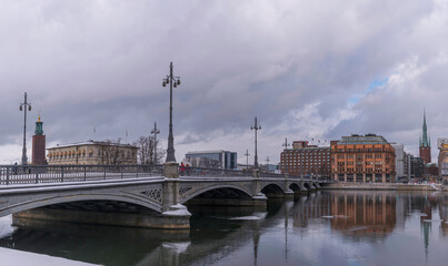 The bridge Vasabron at the river Stömmen, churches, Town City Hall and offices, a grey snowy day in Stockholm