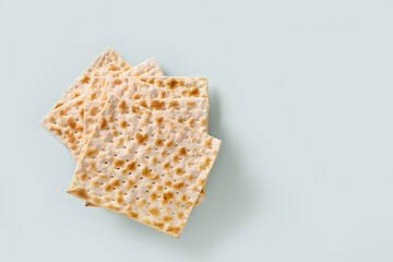 Traditional Jewish kosher matzo for Passover isolated on blue background. Pesach Jewish holiday. Top view. Copy space.