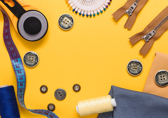 Frame made of sewing tools on a yellow background. Roller cutter, bobbins, zippers, buttons, textile, measuring tape. Flat lay. Copy space.