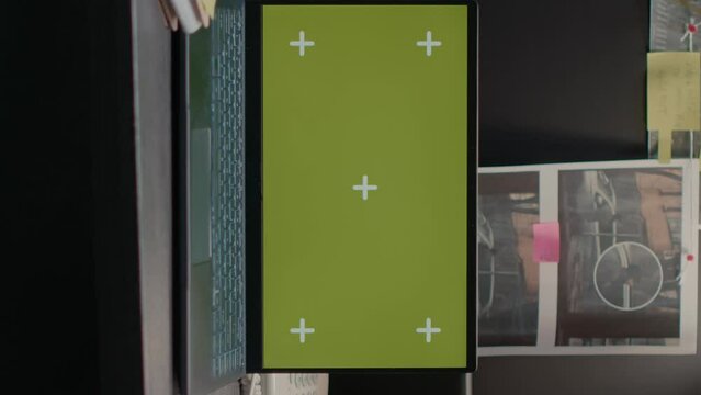 Vertical video: Greenscreen display on portable laptop in incident room, isolated chroma key template. Wireless computer placed on desk showing blank copyspace mockup screen, evidence board map.