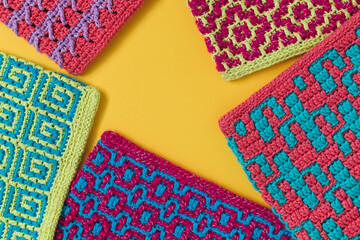Colorful mosaic crochet texture with copy space on a yellow background.