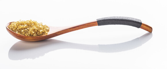 coarse yellow sea salt in a wooden spoon, isolated on a white background with reflection