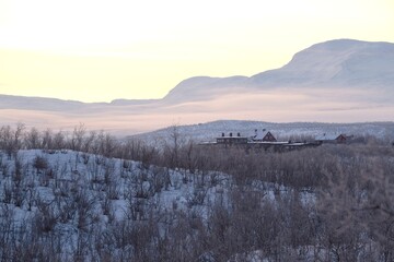 Beautiful sunrise at Abisko Ostra viewpoint. Snowy scenery of mountains and buildings in valley. Abisko National Park (Abisko nationalpark), Sweden, Arctic Circle, Swedish Lapland