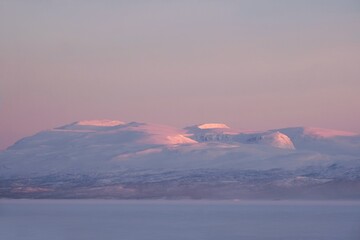 Beautiful sunrise at Abisko Ostra viewpoint. Snowy scenery of mountains. Abisko National Park (Abisko nationalpark), Sweden, Arctic Circle, Swedish Lapland