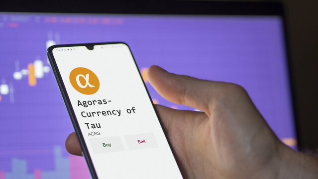 March 11 2023 London UK. An investor's analyzing the Agoras- Currency of Tau  coin on screen. A phone shows the crypto's prices to invest in AGRS