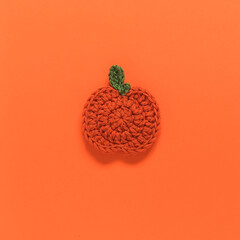 Flat crochet pumpkin close up on an orange background. Top view. Copy space.