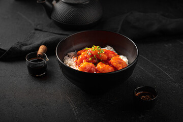 Portion of asian sweet and sour shrimp with rice on black background