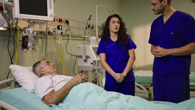 Slow-motion shot of a female doctor with curly hair and medical stuffs talking to the senior patient in hospital bed