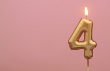 Burning gold birthday candle on pink background, number 4. Large copy space for text.