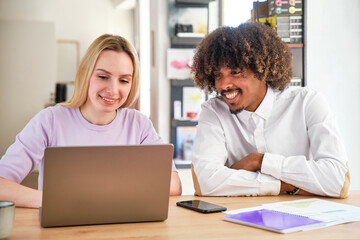 Fototapeta na wymiar african american guy with afro hair and long haired blonde caucasian girl in a coworking