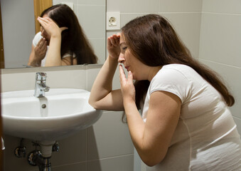 A pregnant woman struggling with morning sickness at the bathroom holding her head