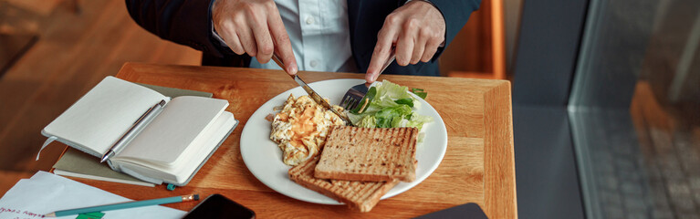 Close up of businessman taking a breakfast before starting working day in cafe